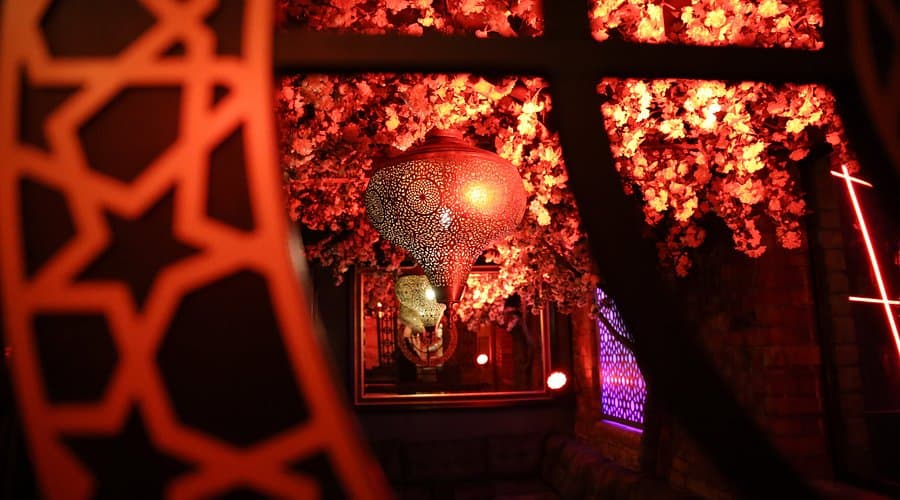 View through ornate lattice gates with cherry blossoms and warm ambient lighting inside Junoon Cafe